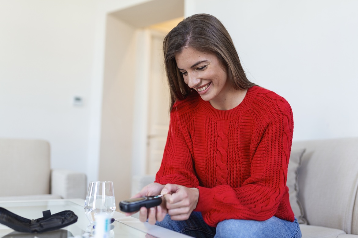 Patient performing a blood glucose test at home as part of diabetes management and remote patient monitoring.