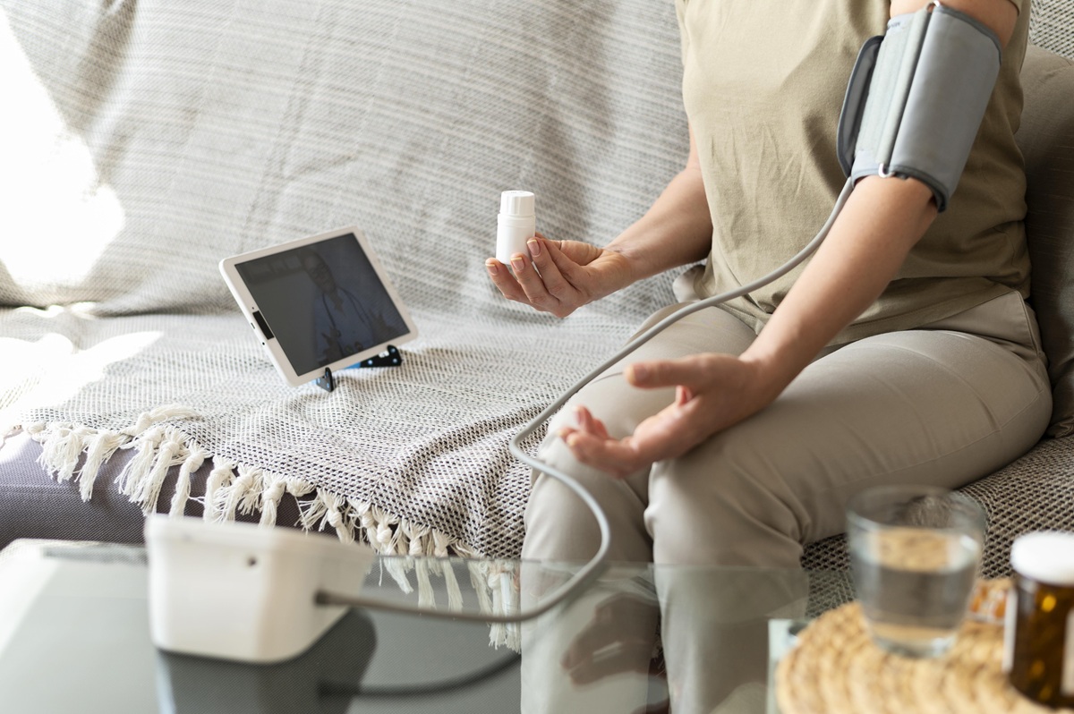 Patient using a remote patient monitoring device at home while sharing health data with a healthcare provider to support RPM adherence and chronic disease management